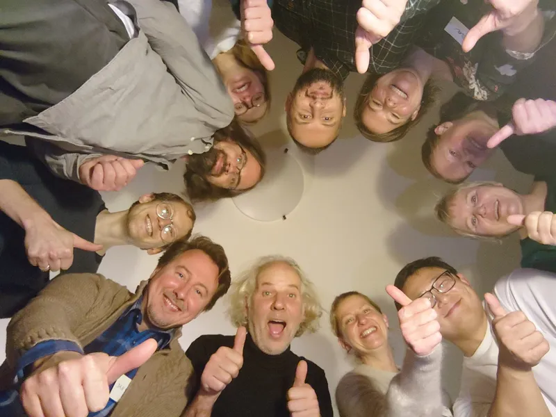 group of people in a circle doing a thumbs up