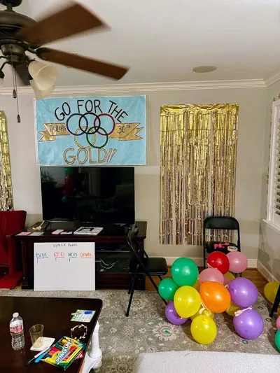 Gold streamers, hanging stars, and star lanyards decorating a Go for the Gold themed 30th birthday party venue