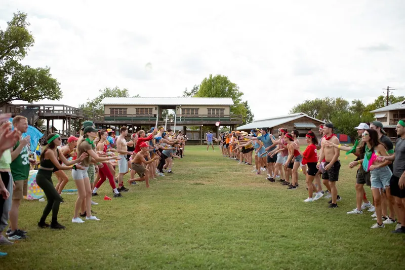 Adult summer camp members doing water balloon toss