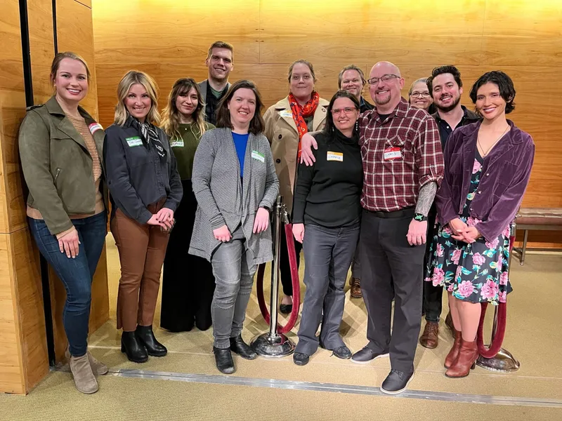 A group of people with name tags smiling and standing.