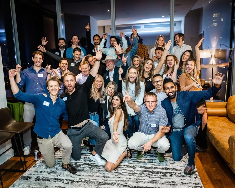 group of people smiling and raising their hands