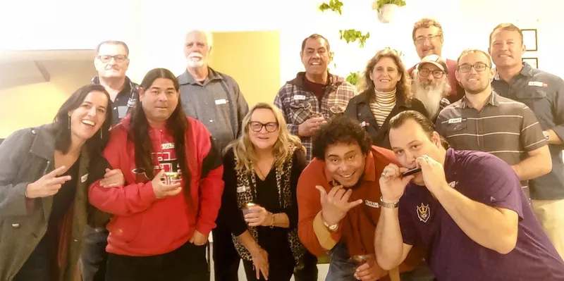 group of people smiling, one with a harmonica