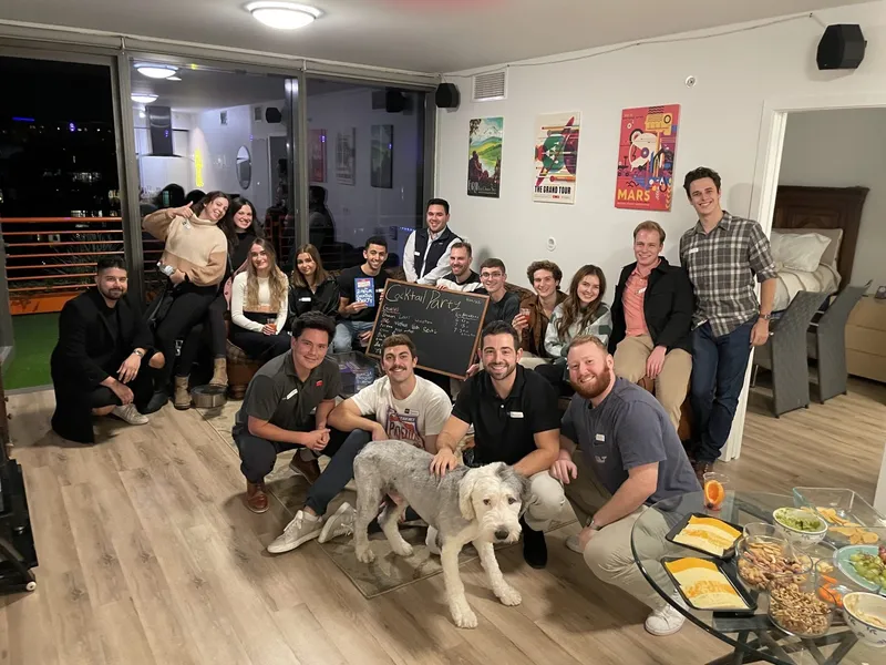 group of people with name tags smiling with a blackboard and a dog in the middle
