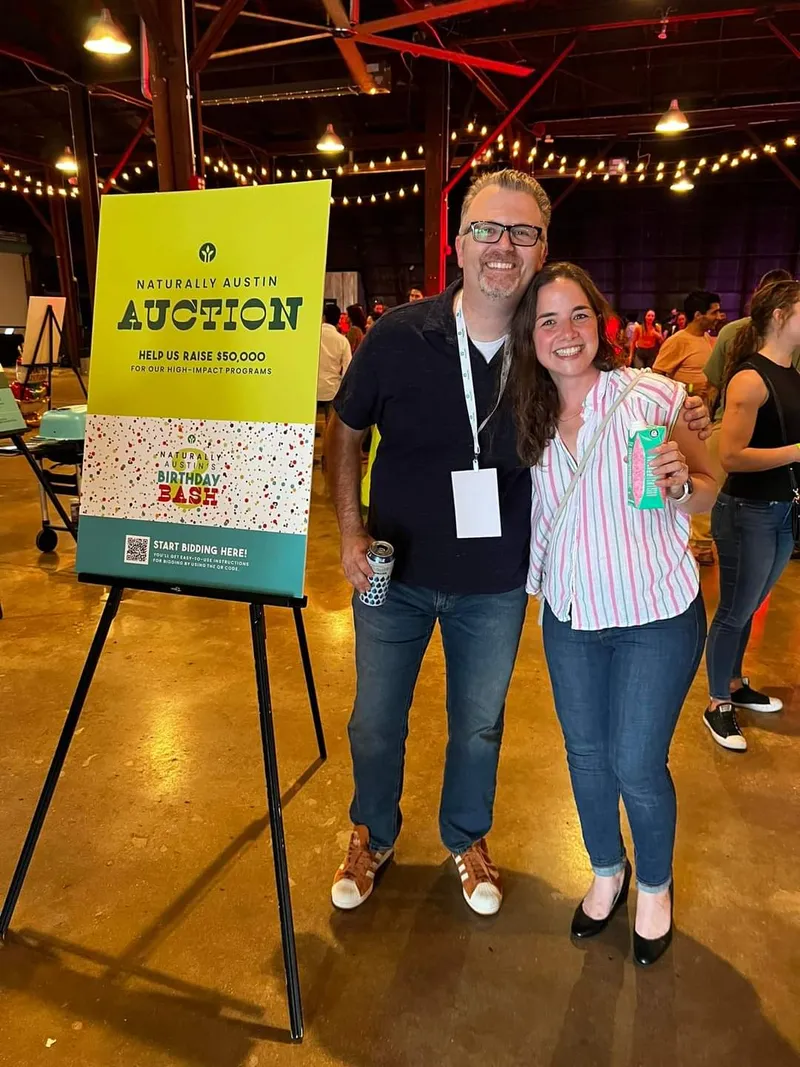 man and woman posing with sign on the left saying "auction"