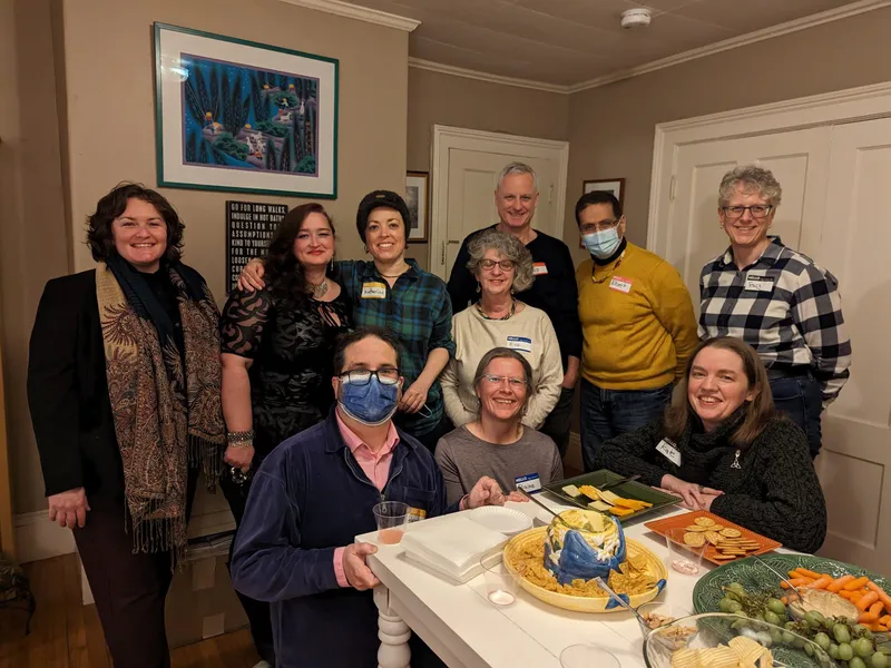 A group of people with name tags smiling, two of them are wearing face masks.
