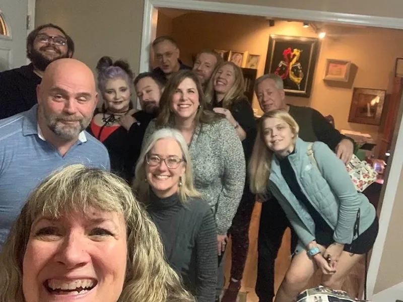 A group of people smiling, indoors, and looking at the camera.